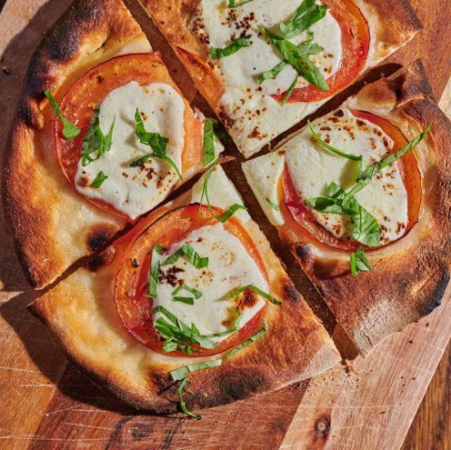 Margherita flatbread with tomato, mozzarella and basil, cut into quarters