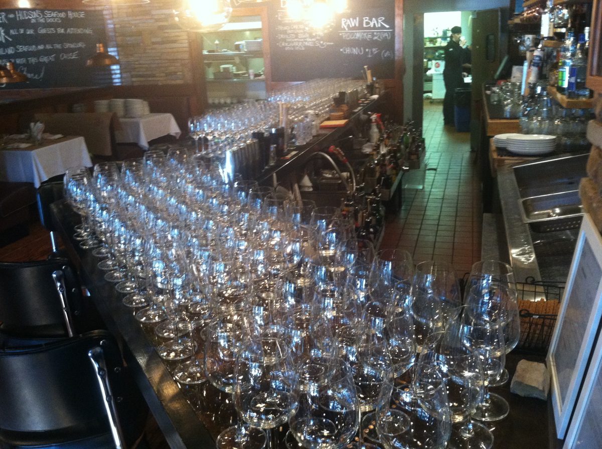Rows of wine glasses set up on a restaurant bar before service