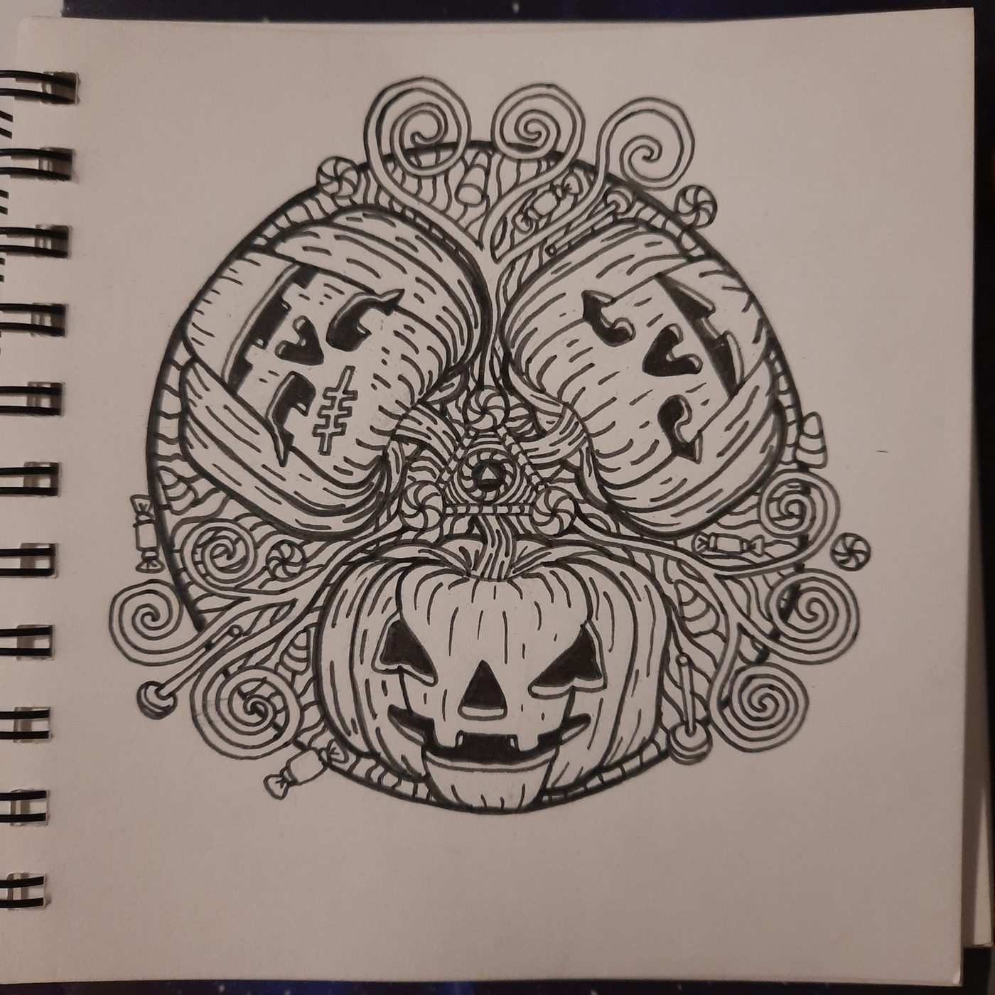 Ink drawing of three jack-o’-lanterns wrapped in swirls and candy